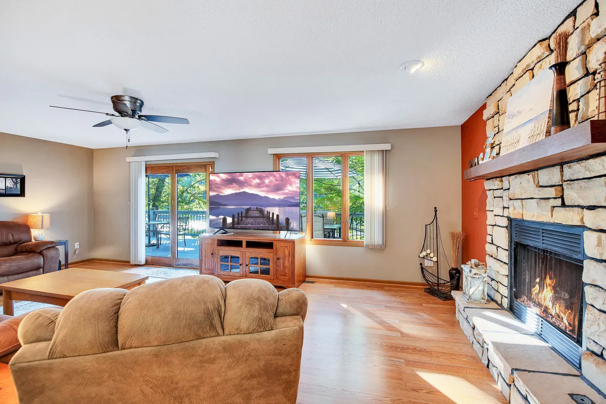 A second living area is shown here with comfortable seating, a large television, and a stone fireplace. The room is arranged for both relaxation and entertainment, highlighting a space where guests can unwind or enjoy movie nights together.