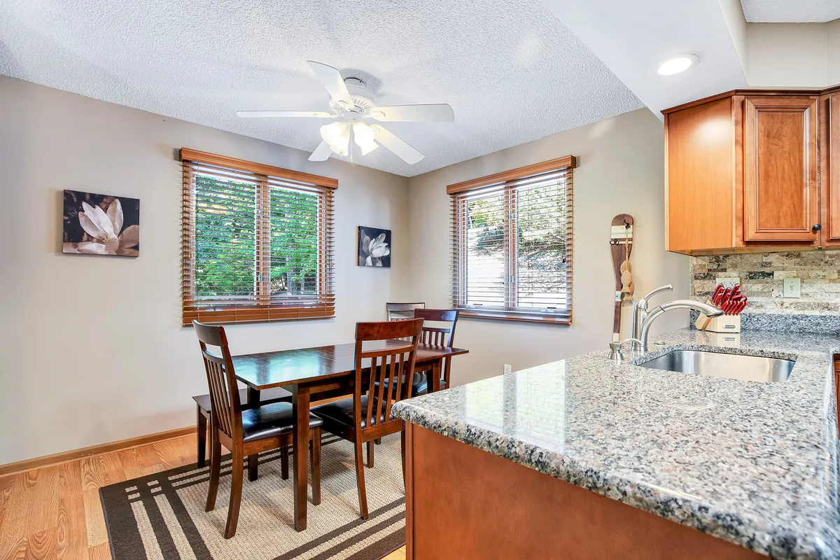 A spacious dining area with a large dining table, kitchen island, and expansive windows offering views of greenery. The setting is styled for family meals, casual gatherings, and quiet moments, tying together kitchen and dining experiences.
