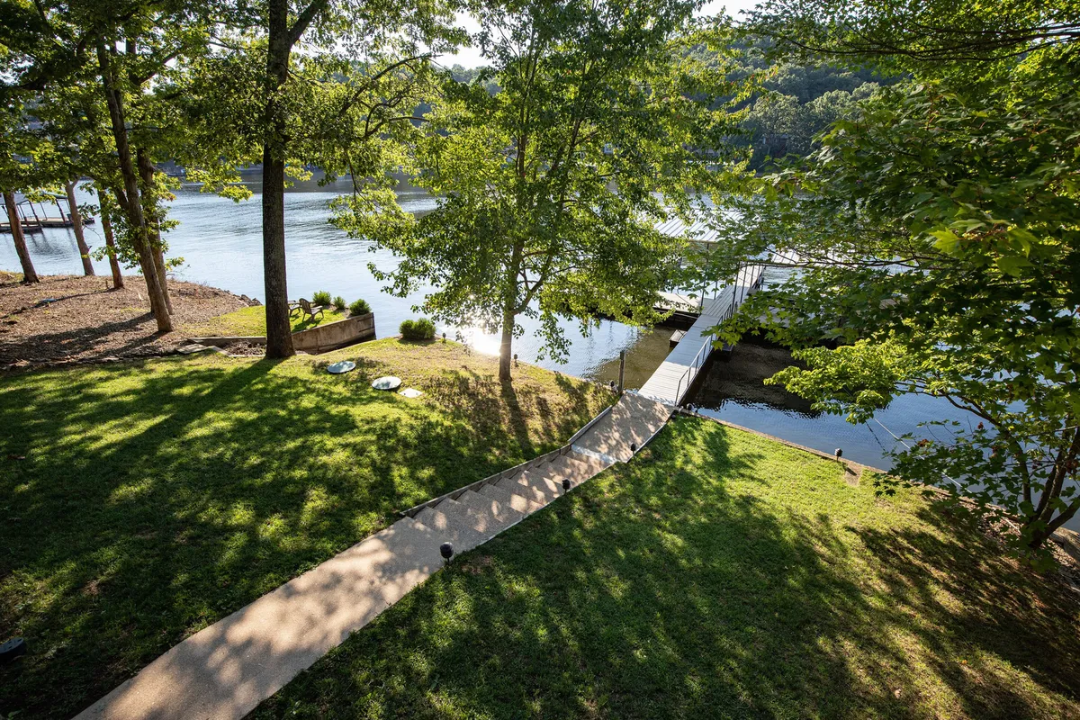 This image features a pathway that leads directly to the dock, surrounded by lush greenery and overlooking a calm water surface. The peaceful setting hints at activities like boating, fishing, and enjoying the lakeside environment.